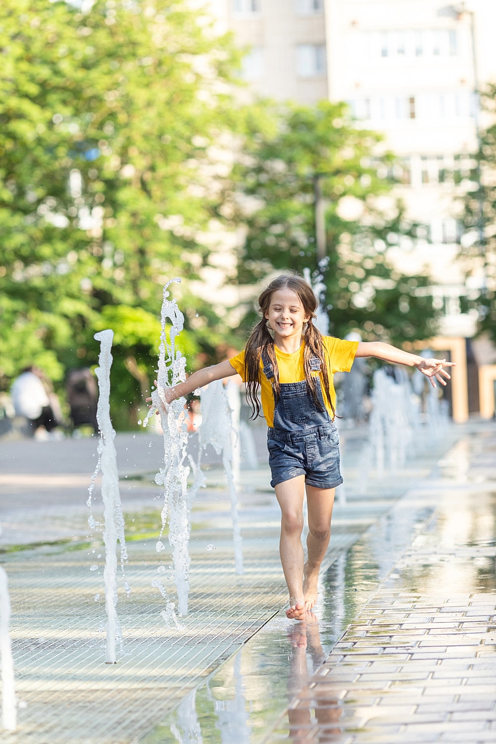 Child playing joyfully in a fountain.