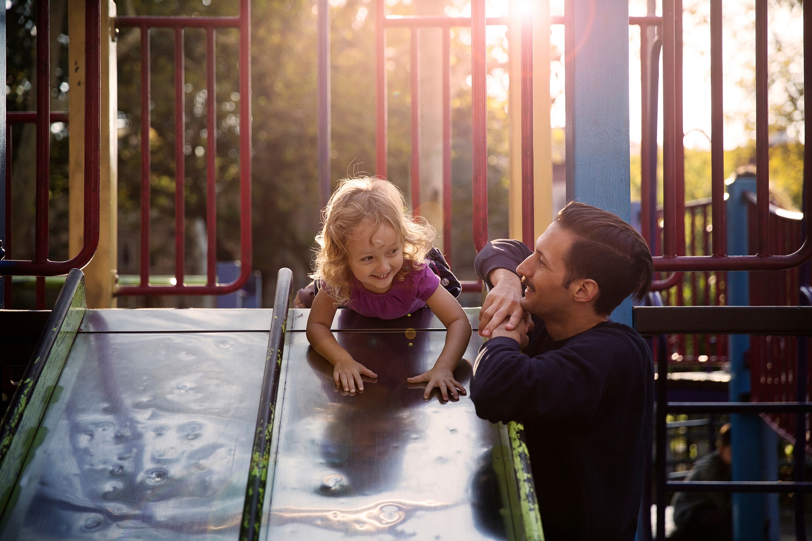 Child playing on a slide with an adult.