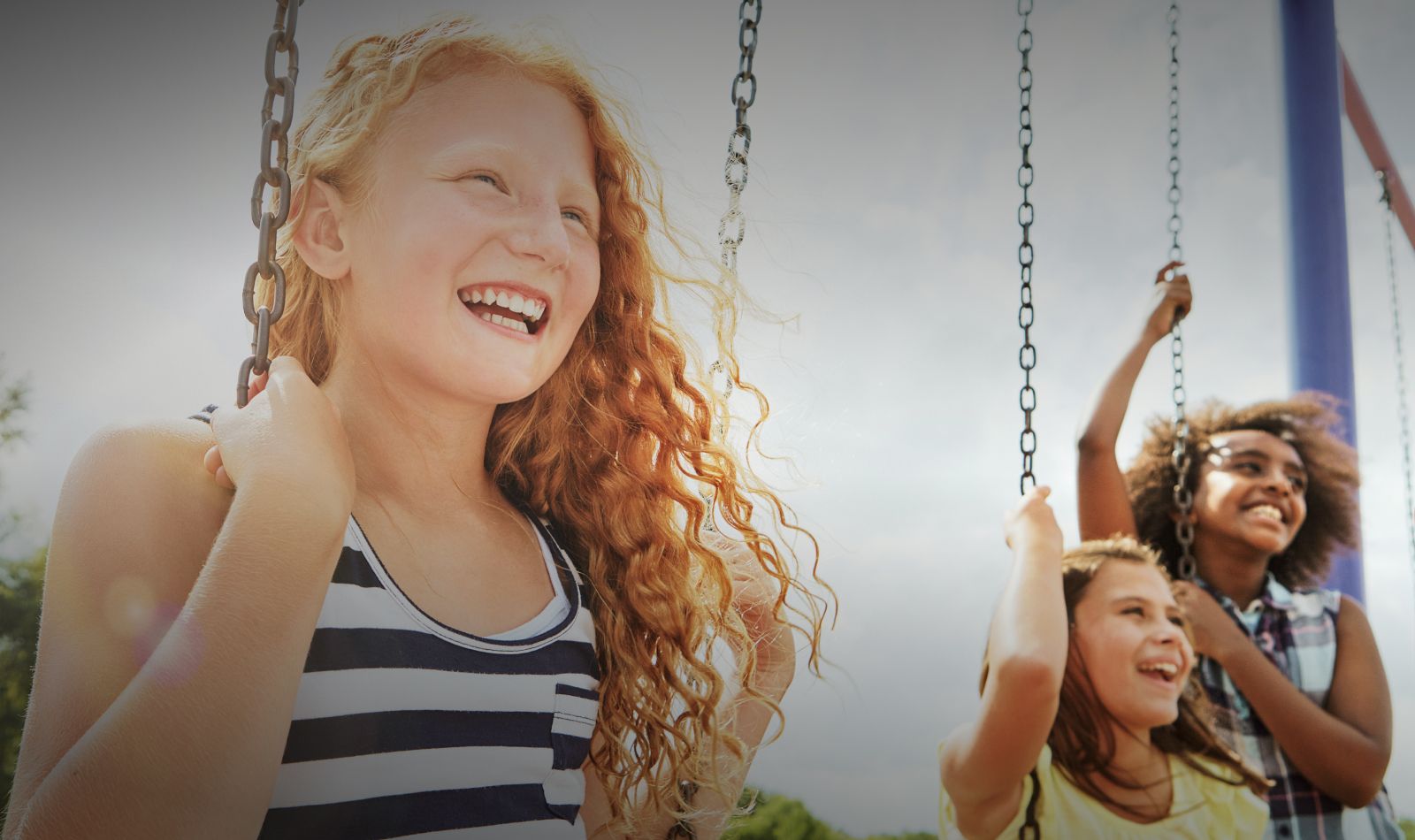 Children happily playing on swings outdoors.