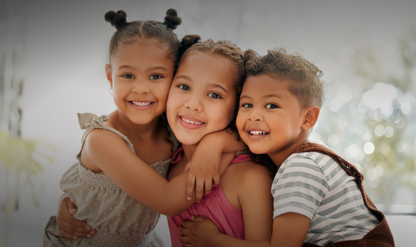 Three children smiling and embracing together.